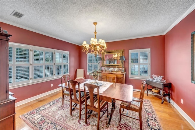 dining room featuring ornamental molding, a chandelier, light hardwood / wood-style floors, and a textured ceiling