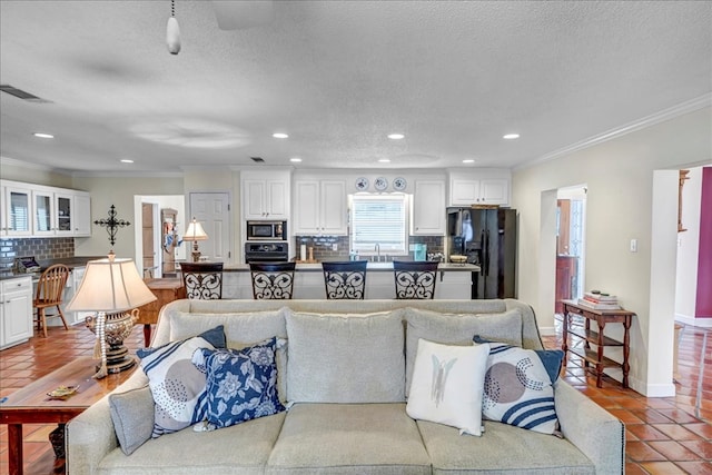 living room with light tile patterned floors, crown molding, sink, and a textured ceiling