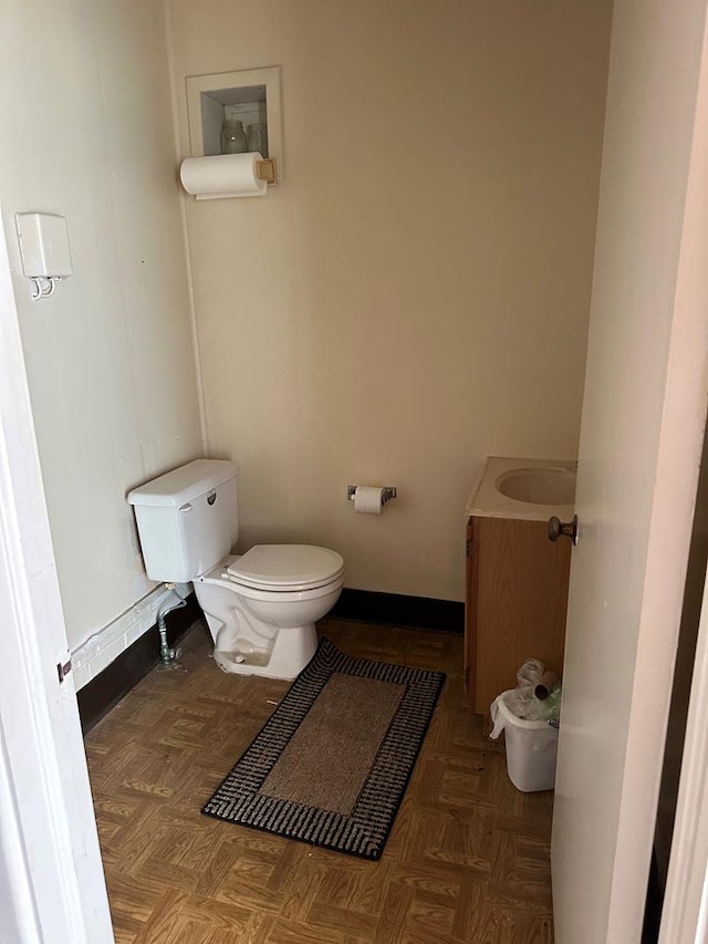 bathroom featuring vanity, toilet, and parquet floors