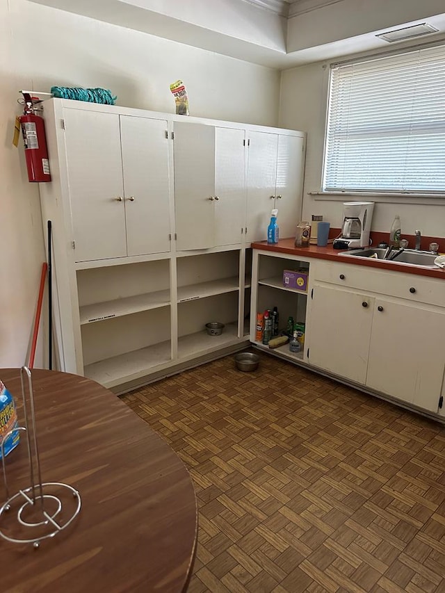 kitchen featuring sink, dark parquet floors, and white cabinets