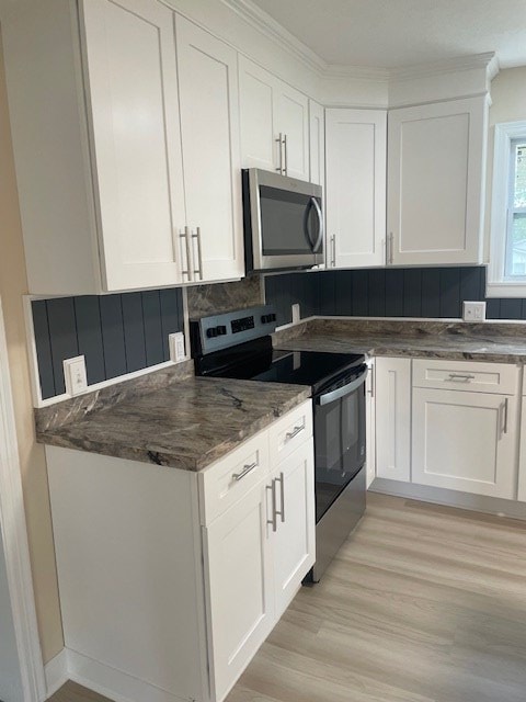510 E 25th Ave, Cordele, GA 31015 - kitchen with stainless steel appliances, light wood finished floors, white cabinetry, dark stone countertops, and decorative backsplash