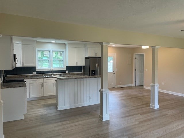 510 E 25th Ave, Cordele, GA 31015 - kitchen with stainless steel fridge with ice dispenser, white cabinetry, light wood-type flooring, decorative columns, and a kitchen island