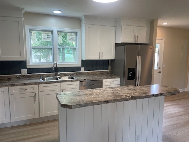510 E 25th Ave, Cordele, GA 31015 - kitchen featuring appliances with stainless steel finishes, a sink, light wood-style floors, white cabinetry, and a center island