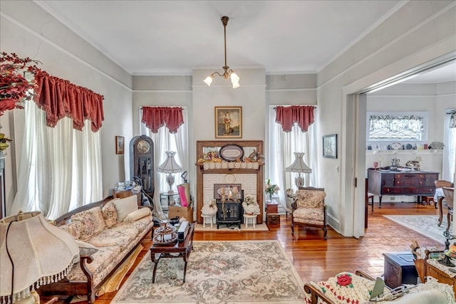 living room with a wood stove, an inviting chandelier, crown molding, and wood-type flooring