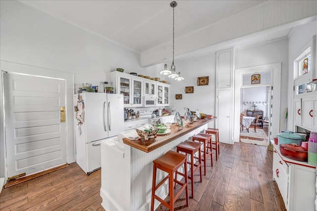 kitchen featuring decorative light fixtures, dark wood-type flooring, white cabinetry, white appliances, and a kitchen island