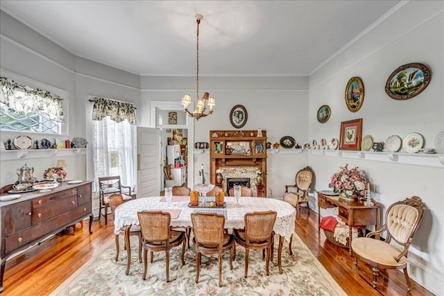 dining space with crown molding, an inviting chandelier, and light wood-type flooring