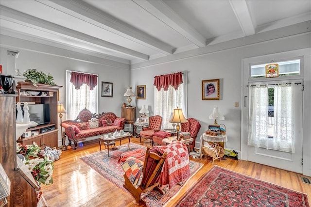 living room with hardwood / wood-style floors, beam ceiling, and a wealth of natural light