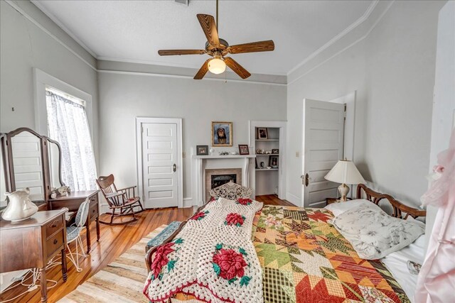 bedroom with crown molding, light hardwood / wood-style floors, and ceiling fan