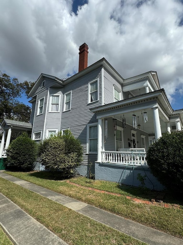 view of home's exterior with covered porch and a yard