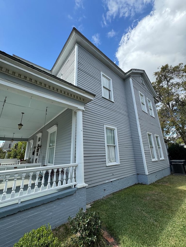 view of side of home with covered porch and a lawn