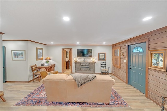 living room featuring light hardwood / wood-style floors, wooden walls, and ornamental molding