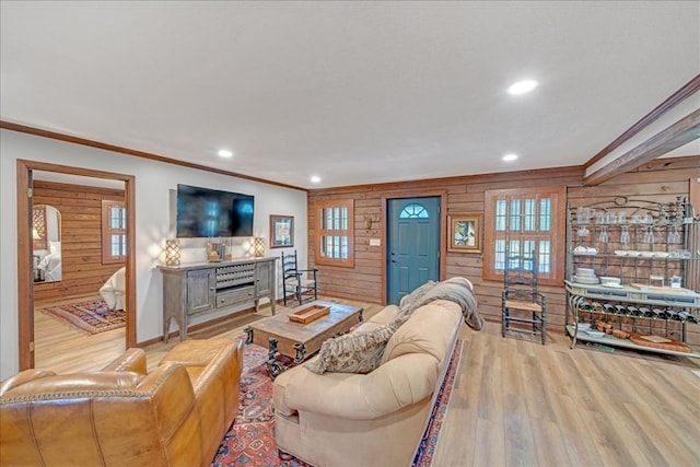 living room with light hardwood / wood-style floors, ornamental molding, and wood walls