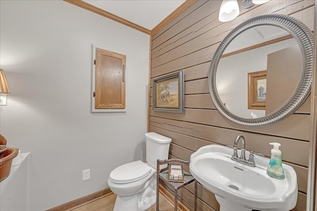 bathroom with sink, crown molding, toilet, and wood walls