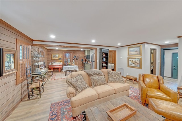 living room featuring crown molding, light hardwood / wood-style floors, and wooden walls