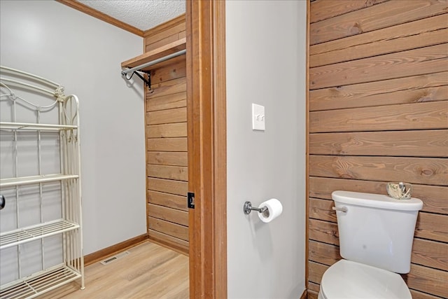 bathroom featuring crown molding, hardwood / wood-style floors, a textured ceiling, and toilet