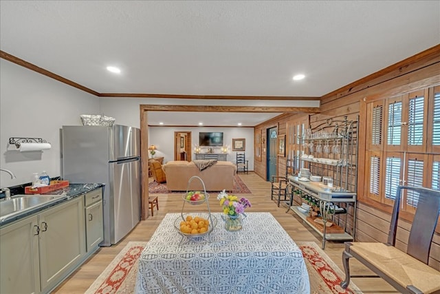 kitchen with crown molding, stainless steel refrigerator, sink, light hardwood / wood-style flooring, and pendant lighting