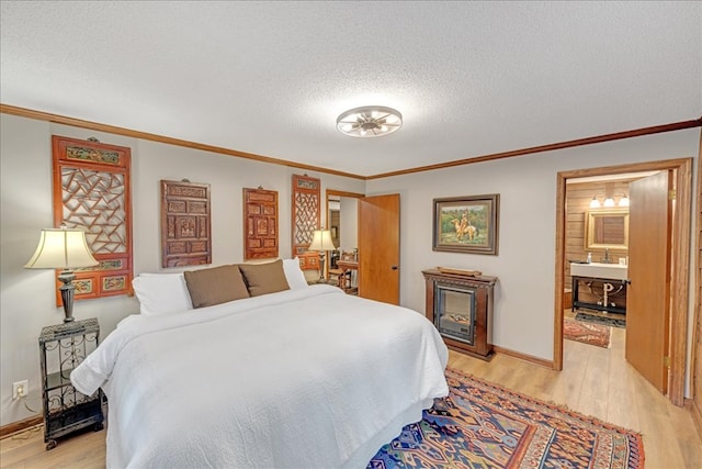 bedroom featuring a textured ceiling, light hardwood / wood-style flooring, connected bathroom, and ornamental molding