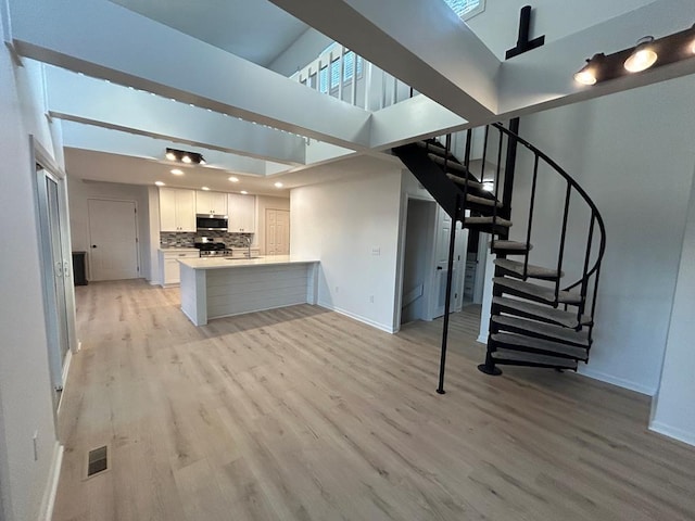 interior space featuring a towering ceiling and light hardwood / wood-style flooring