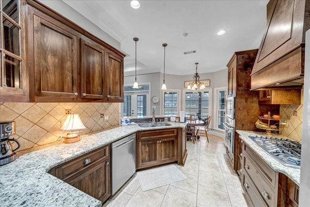 kitchen featuring hanging light fixtures, sink, tasteful backsplash, light stone counters, and stainless steel appliances