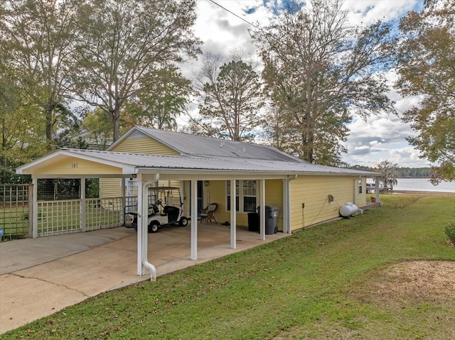 back of property with a yard, a water view, and a carport