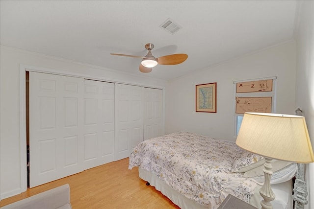 bedroom with wood-type flooring, a closet, ceiling fan, and ornamental molding