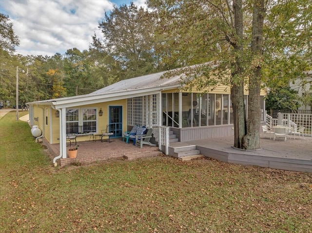 back of property featuring a lawn, a sunroom, a patio area, and a deck