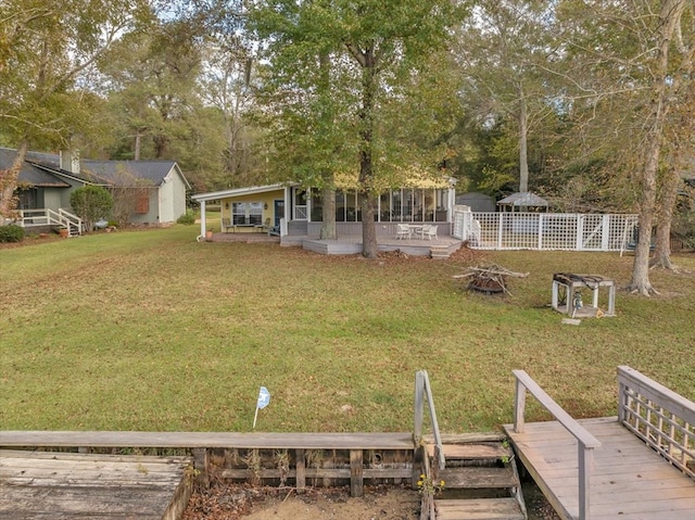 view of yard featuring a sunroom, an outdoor fire pit, and a deck