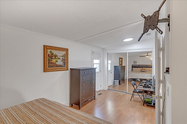 bedroom featuring a closet, light wood-type flooring, crown molding, and a textured ceiling