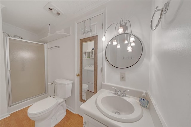 bathroom with a textured ceiling, washer / clothes dryer, wood-type flooring, vanity, and toilet