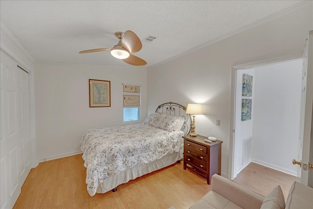 bedroom with crown molding, light hardwood / wood-style floors, a textured ceiling, a closet, and ceiling fan