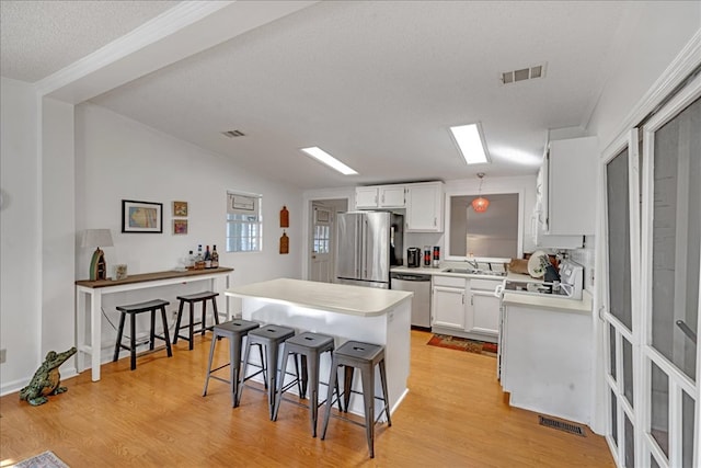 kitchen with white cabinets, stainless steel appliances, sink, and a kitchen breakfast bar