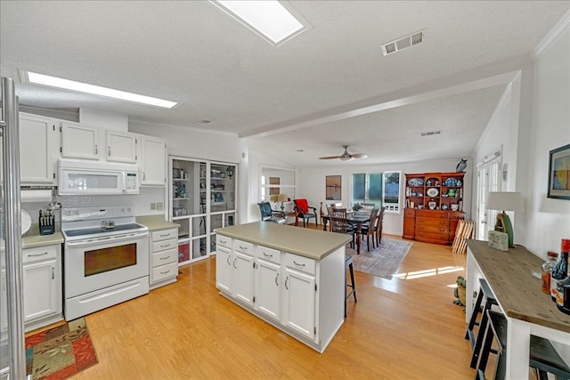 kitchen with a kitchen breakfast bar, white appliances, white cabinetry, and a center island