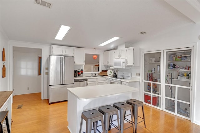 kitchen featuring a kitchen breakfast bar, white cabinets, light hardwood / wood-style floors, and stainless steel appliances