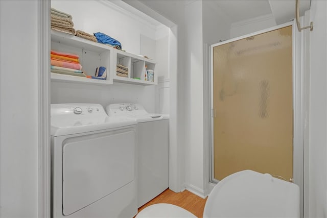 laundry room with light hardwood / wood-style floors, washer and dryer, and ornamental molding