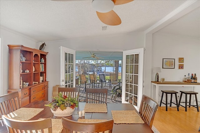 dining area featuring hardwood / wood-style floors, a textured ceiling, ceiling fan, and ornamental molding