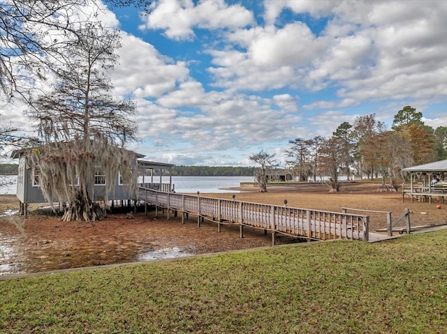 view of dock with a lawn and a water view