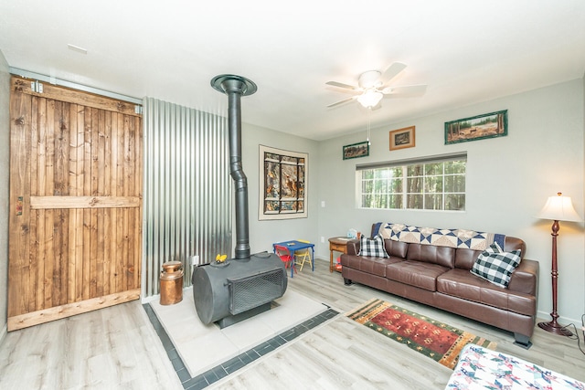 living room featuring ceiling fan, a wood stove, and light hardwood / wood-style flooring