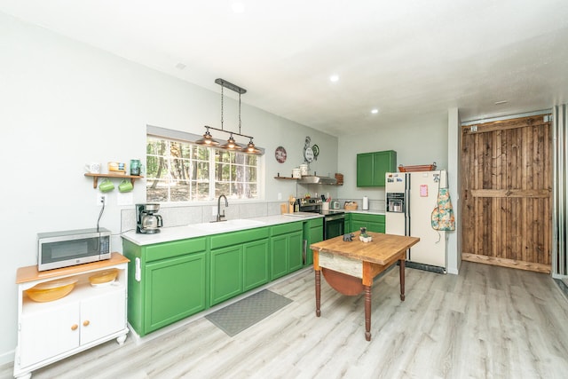 kitchen with sink, hanging light fixtures, light hardwood / wood-style floors, stainless steel appliances, and green cabinetry