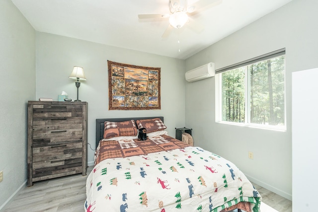 bedroom with ceiling fan, light wood-type flooring, and a wall unit AC