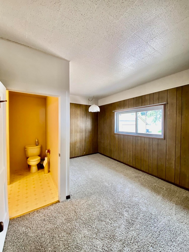 carpeted empty room featuring wood walls and a textured ceiling