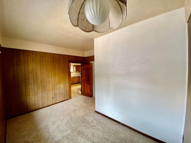 unfurnished room with light carpet and wooden walls