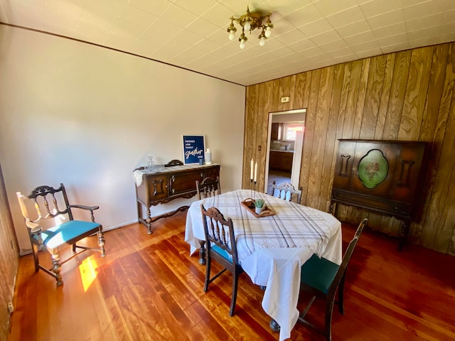 dining space with wood-type flooring and wooden walls