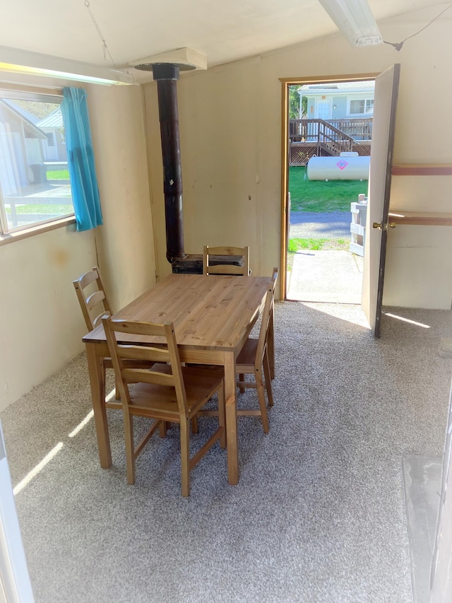 dining room featuring a wood stove, carpet, and a wealth of natural light