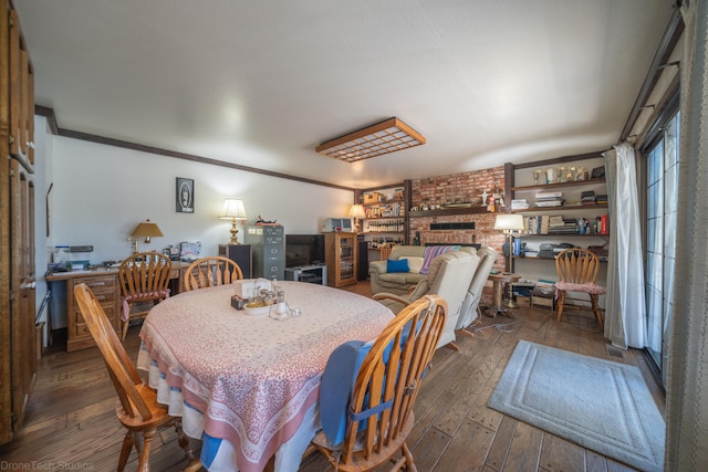 dining room featuring brick wall, dark hardwood / wood-style floors, and a brick fireplace