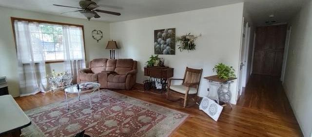 living area featuring ceiling fan and dark hardwood / wood-style flooring