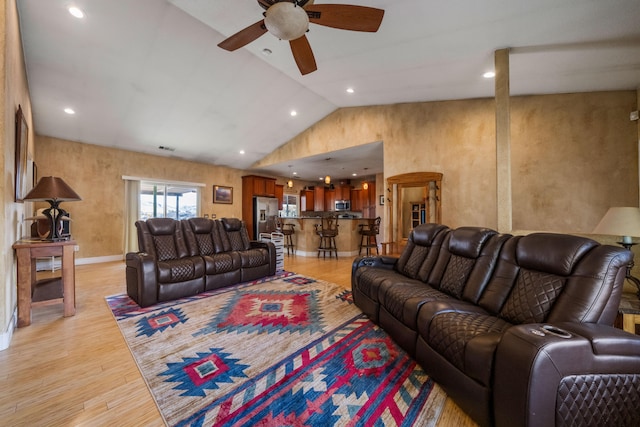 living room with ceiling fan, lofted ceiling, and light hardwood / wood-style flooring