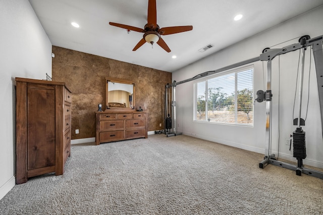 unfurnished bedroom featuring a barn door, light colored carpet, and ceiling fan