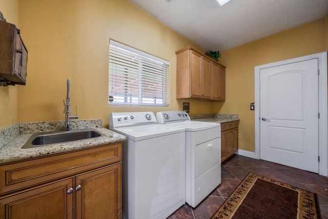 laundry area with dark tile floors, cabinets, sink, and washing machine and dryer