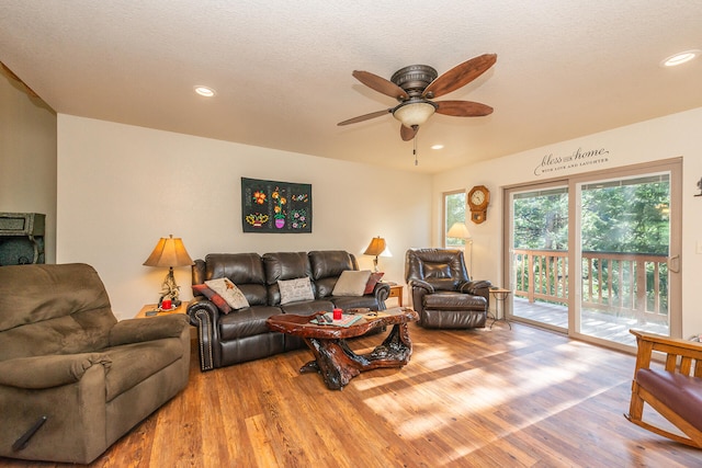 living room featuring a textured ceiling, light hardwood / wood-style floors, and ceiling fan