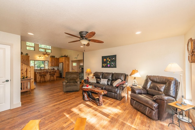 living room featuring light hardwood / wood-style floors, a textured ceiling, and ceiling fan